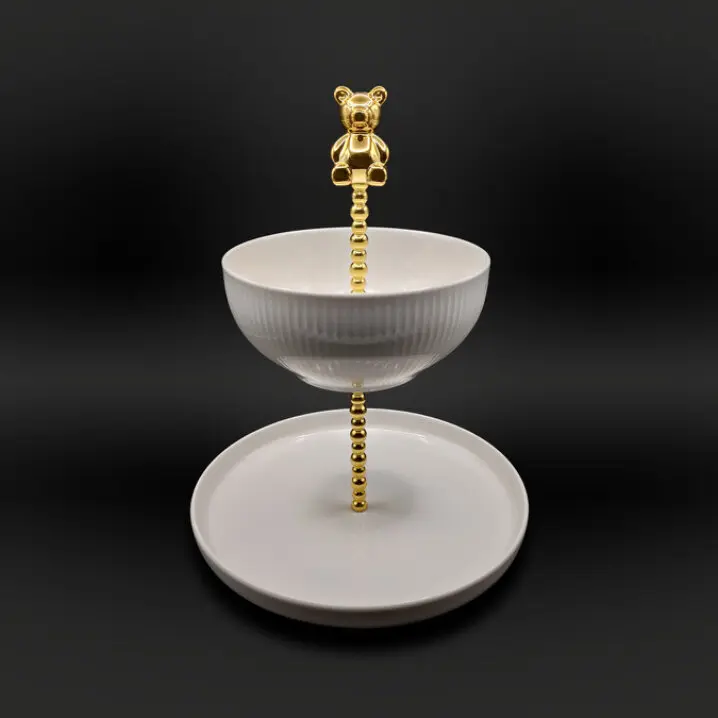 Zweistöckige Etagere mit weißem Teller und Schale, goldfarbene Stange mit Bärfigur als Griff