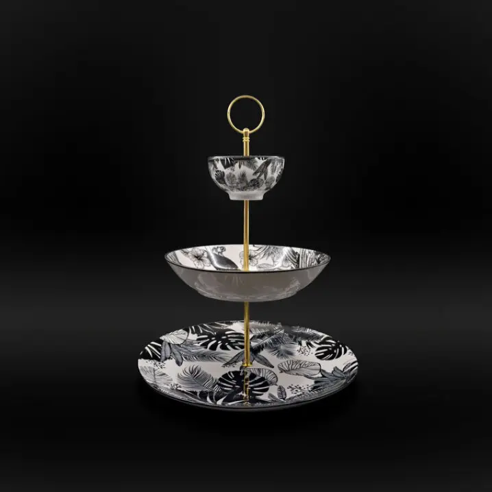 Dreistufige Etagere mit goldfarbener Metallstange und Ringgriff; oben kleine Schale, in der Mitte flacher Teller, unten großer Teller, jeweils mit schwarz-weißem Pflanzenmuster, vor schwarzem Hintergrund