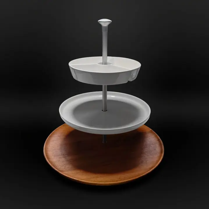 Dreistöckige Etagere mit einem Holztablett unten, einem grauen Teller in der Mitte und einem weißen, dreigeteilten Teller oben