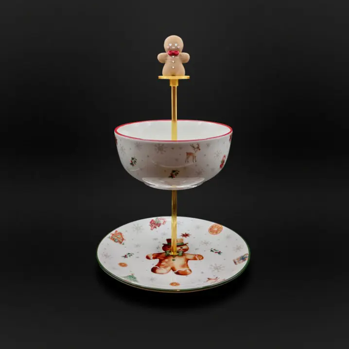 Zweistufige Weihnachts-Etagere mit goldfarbener Stange und Lebkuchenmann als Griff; oben weiße Schale mit rotem Rand, unten Teller mit Lebkuchenmann-Motiv, vor dunklem Hintergrund.