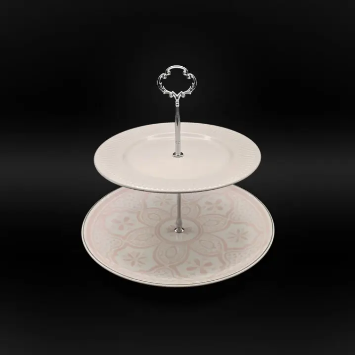 Zweistufige Etagere mit silberfarbenem Metallständer und Herzgriff; oben weißer Teller, unten Teller mit zart rosafarbenem Ornamentmuster, vor schwarzem Hintergrund.