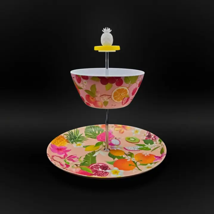 Zweistufige Etagere mit bunter Obst- und Blumenmusterung; oben eine Schale, unten ein Teller, Metallstange mit Ananas-Griff, vor schwarzem Hintergrund.