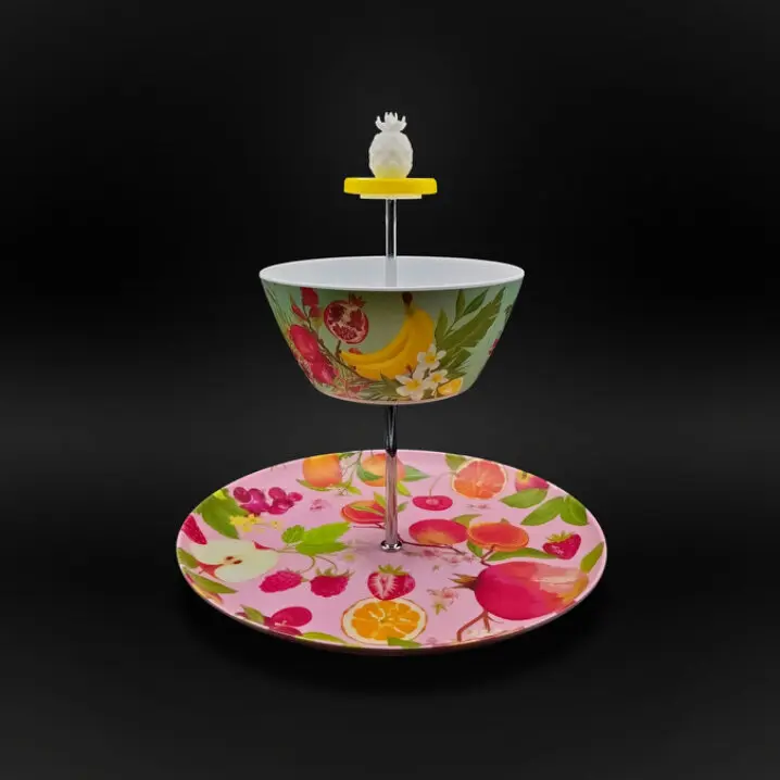 Zweistufige Etagere mit bunter Obst- und Blumenmusterung; oben eine Schale, unten ein Teller, Metallstange mit Ananas-Griff, vor schwarzem Hintergrund.