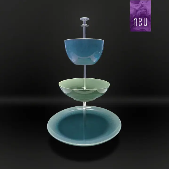 Dreistufige Etagere mit blauer Schale oben, grüner Schale in der Mitte und blauem Teller unten, auf Metallstange vor schwarzem Hintergrund.