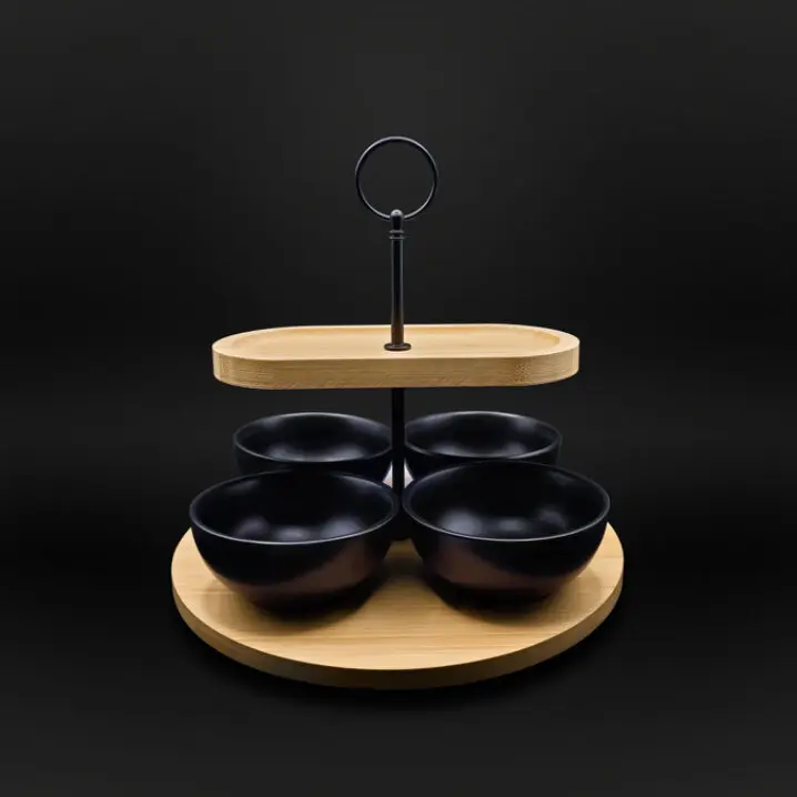 Etagere mit rundem Holztablett unten, ovalem Holztablett oben, vier schwarzen Schalen und einem mittigen Griff mit Ring